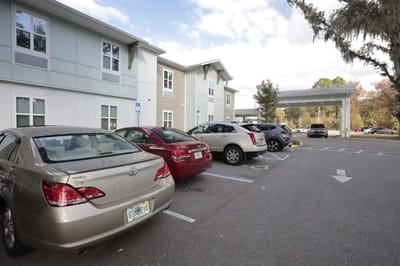 Parking lot view of the facility building with vehicles