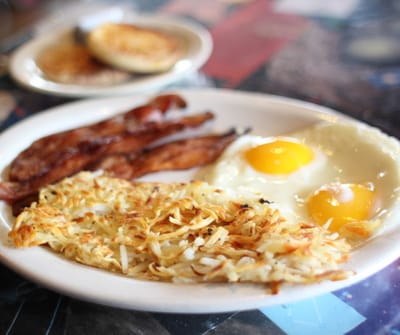 A plate of breakfast with eggs, bacon, and hash browns