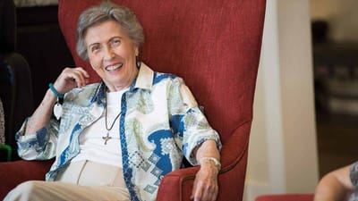 A smiling resident sitting in a cozy chair