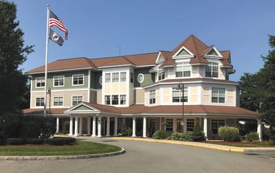 Front exterior of Tamarisk Senior Living with American flag