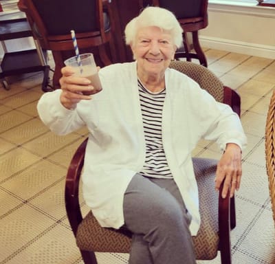 Resident enjoying a drink in a cozy chair