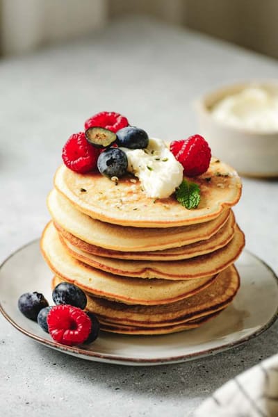 Stack of pancakes topped with berries and cream