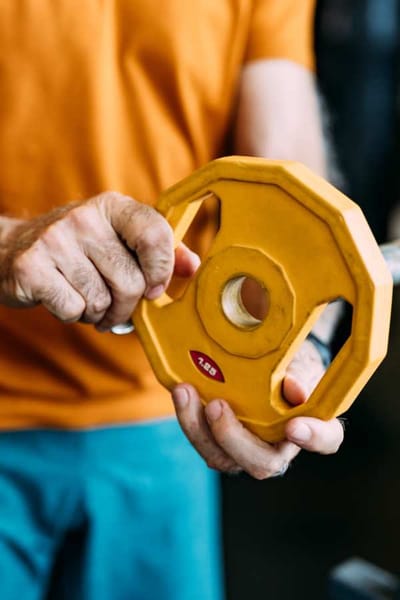 A person's hands holding a yellow weight plate