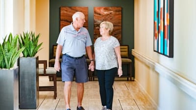 Couple walking hand in hand in a facility hallway