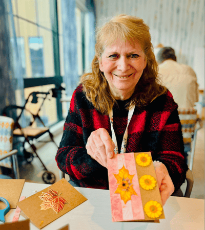 Resident showcasing a craft project in a common area