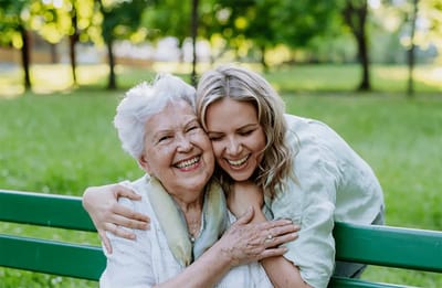 Elderly woman and young woman smiling together outdoors