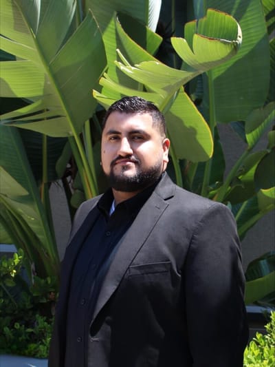 A staff member posed outdoors in front of tropical plants