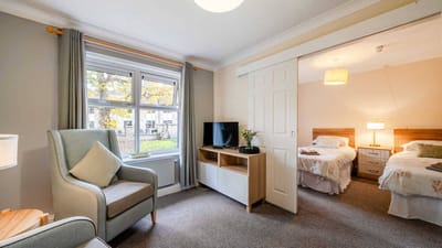 A well-furnished resident room with two beds and a TV