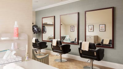 A hair salon area with three mirrors and salon chairs