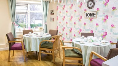 Bright dining area with flowered wallpaper and set tables