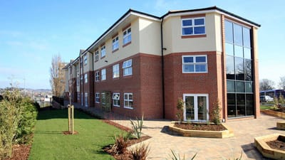 Exterior view of a senior living facility with landscaped garden