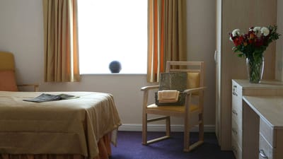 Cozy interior of a resident room with a bed and chair