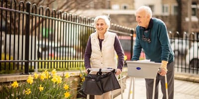 Two residents enjoying a walk outdoors near flowers