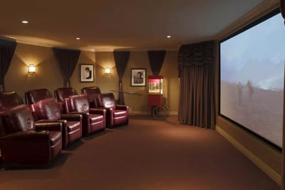 Cozy movie theater with red recliners and a large screen