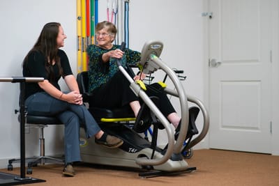 Resident using rehabilitation equipment with staff member