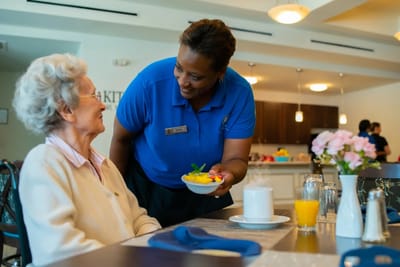 Staff serving a meal to a resident in the dining area