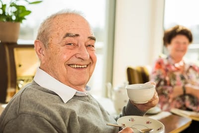 Smiling resident enjoying tea in a common area