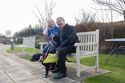 Resident and staff member enjoying time with a therapy dog in the garden