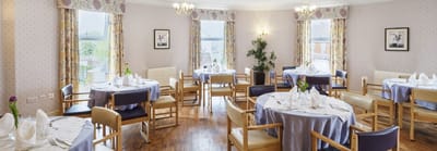A dining room setup with tables and chairs for residents