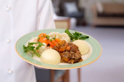 A staff member serving a plate of food in a dining area