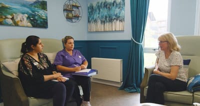 Staff members talking with a resident in a comfortable lounge