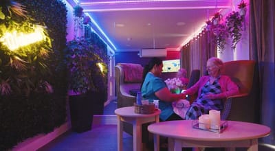 Care staff assisting a resident in a brightly lit room