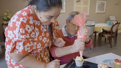 Residents enjoying baking activity with staff in common area