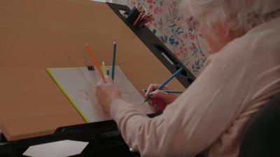 Resident coloring with colored pencils at a desk