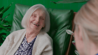 A resident smiling while chatting with staff in a cozy setting