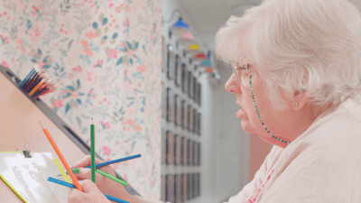 Elderly resident coloring in a brightly lit activity room