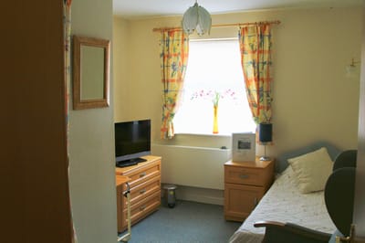 A well-lit private room with a bed and furnishings