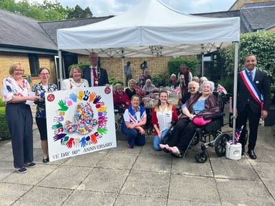 Residents and staff celebrating VE Day anniversary outdoors
