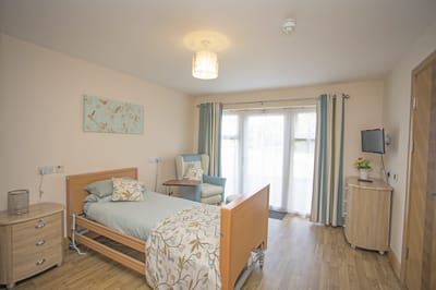 Bright resident room with a hospital bed and seating area