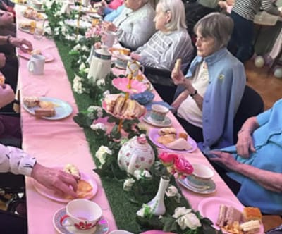 Residents enjoying tea with snacks at a communal table