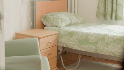 Cozy resident room with green bedding and furniture