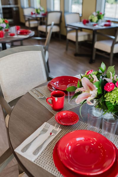 Dining table set with red plates and flowers