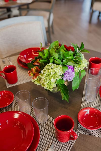 Dining table set with red plates and floral centerpiece