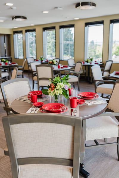 Dining area set with red tableware and flowers