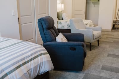A cozy resident room with two beds and a recliner