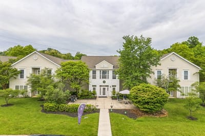Exterior view of The Cottages of Perry Hall with green landscaping.