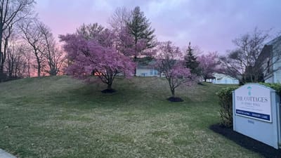 Exterior view of The Cottages of Perry Hall with blooming trees