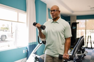 Resident exercising with dumbbells in the fitness area