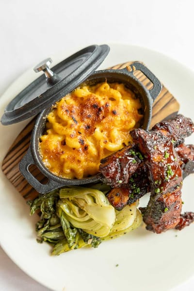 A plate of macaroni and ribs with greens