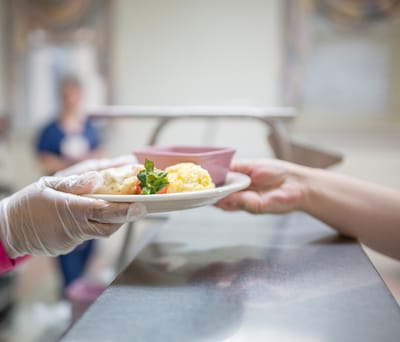 Staff serving a meal to a resident in a dining area