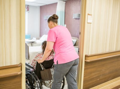 Staff assisting a resident in a hallway of the facility
