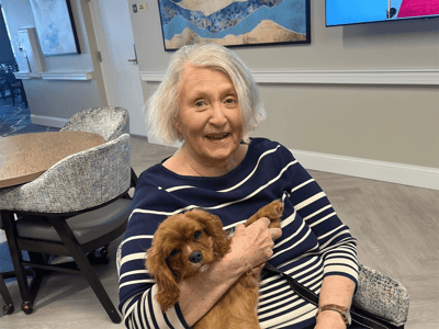 Resident holding a small dog in a common area