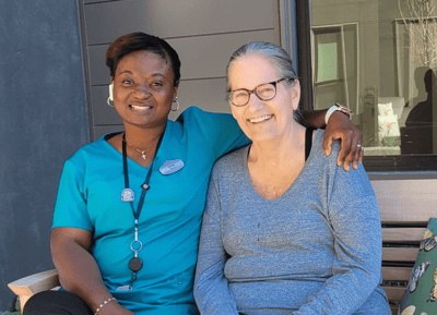 Staff member posing with resident outdoors