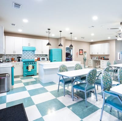 Bright kitchen area with dining tables and teal appliances