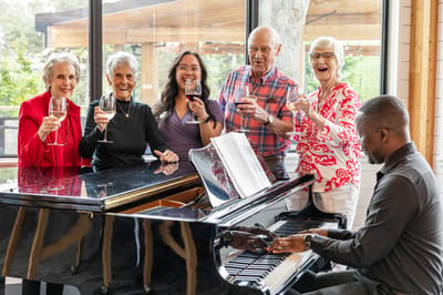 Residents and staff celebrating together at a piano