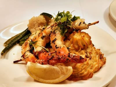 Plated shrimp dish with vegetables and lemon garnish